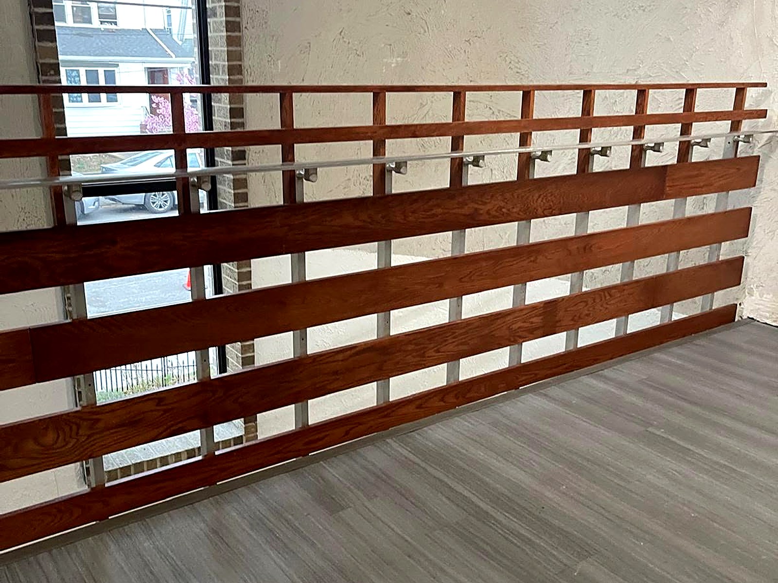 Custom horizontal wood slat railing installed along a renovated mezzanine