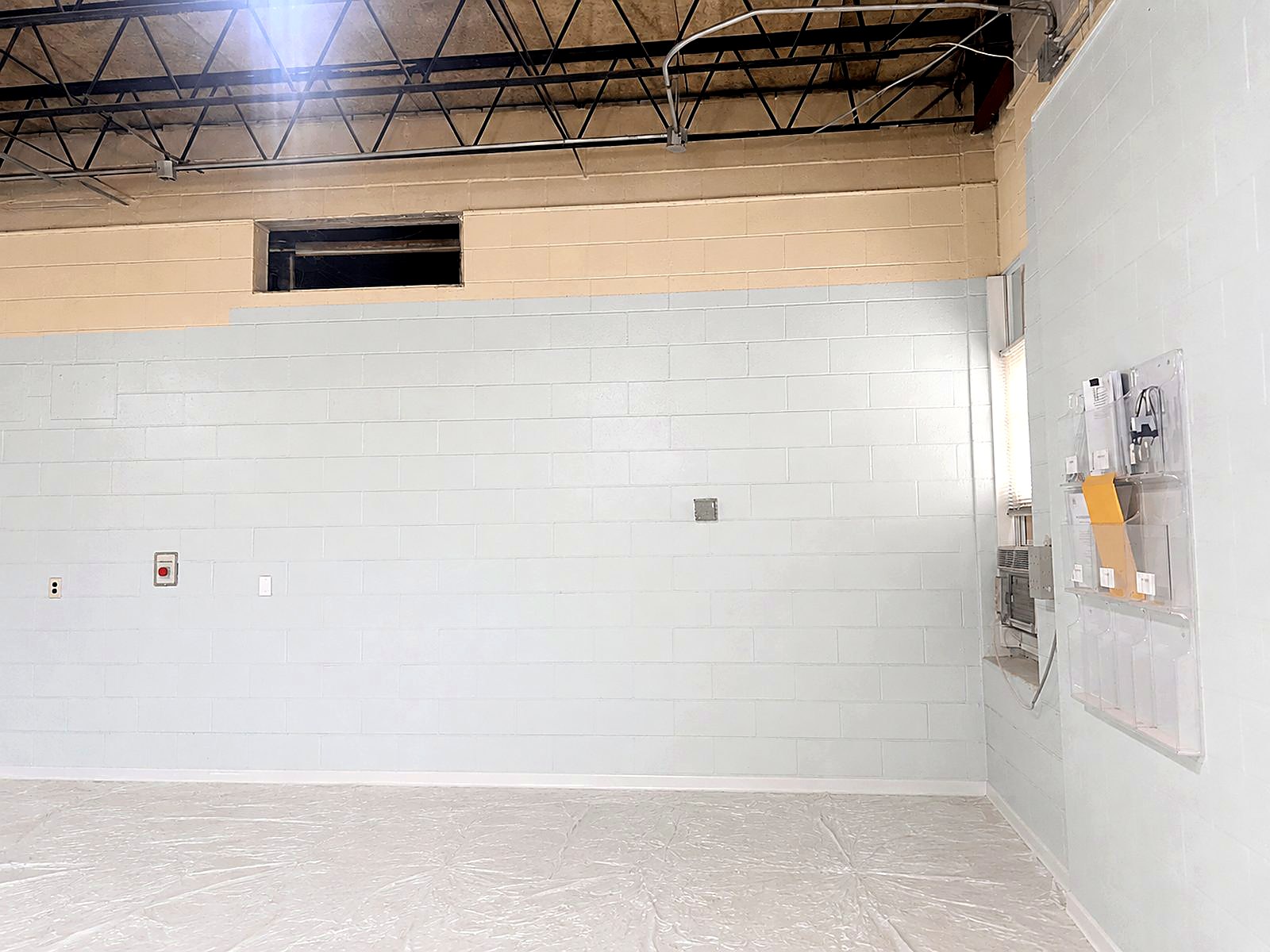 Repainted interior block wall in a commercial space with masked floors