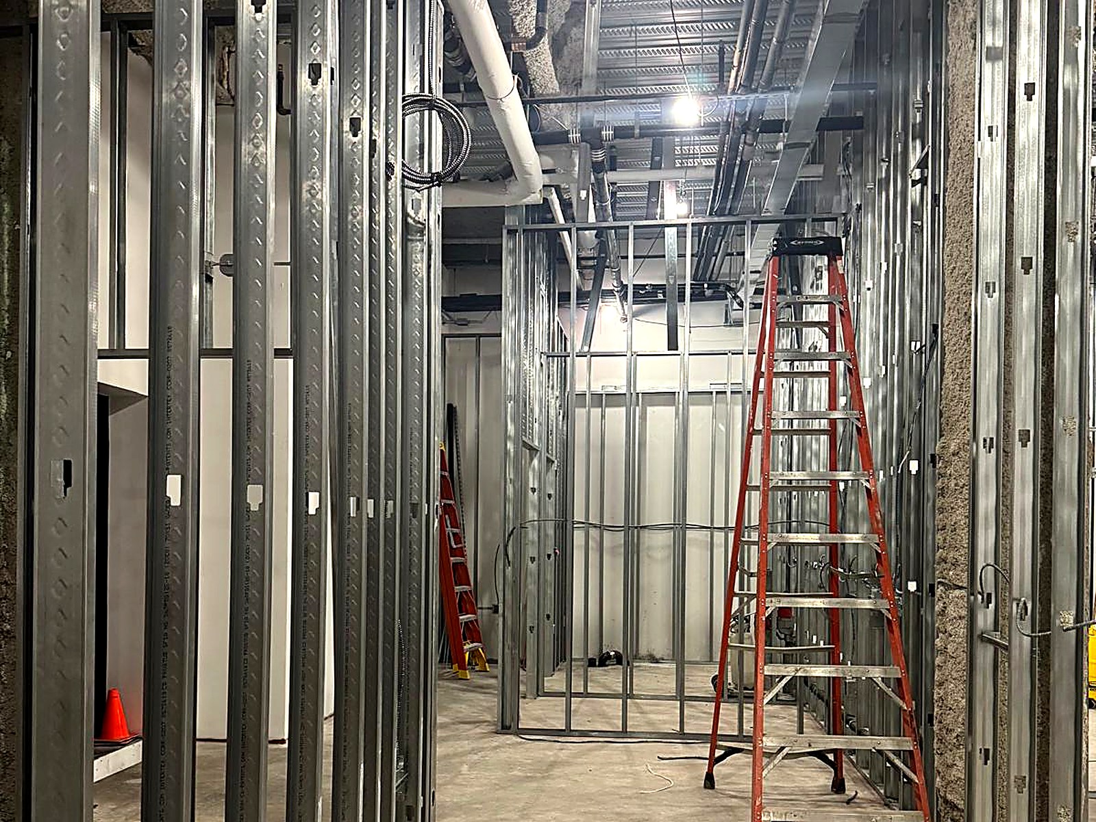 Framed corridor and rooms with overhead piping in a core-and-shell build-out