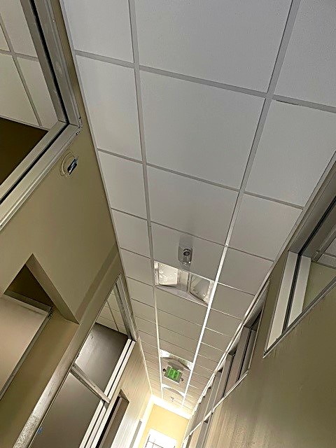 Suspended acoustic tile ceiling installed level and square along a corridor