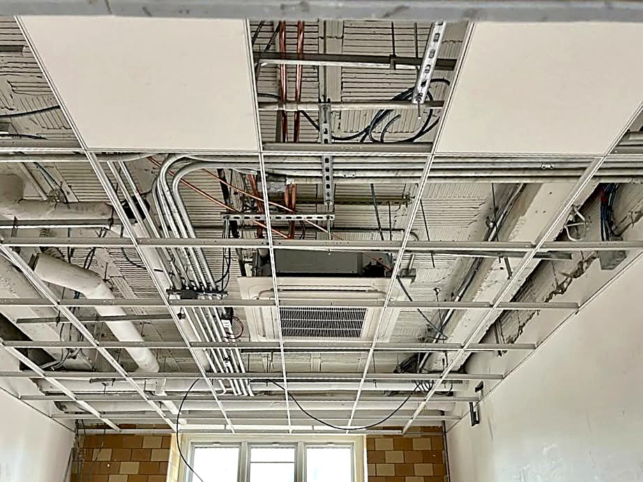 Suspended ceiling grid set level below mechanical and electrical rough-in