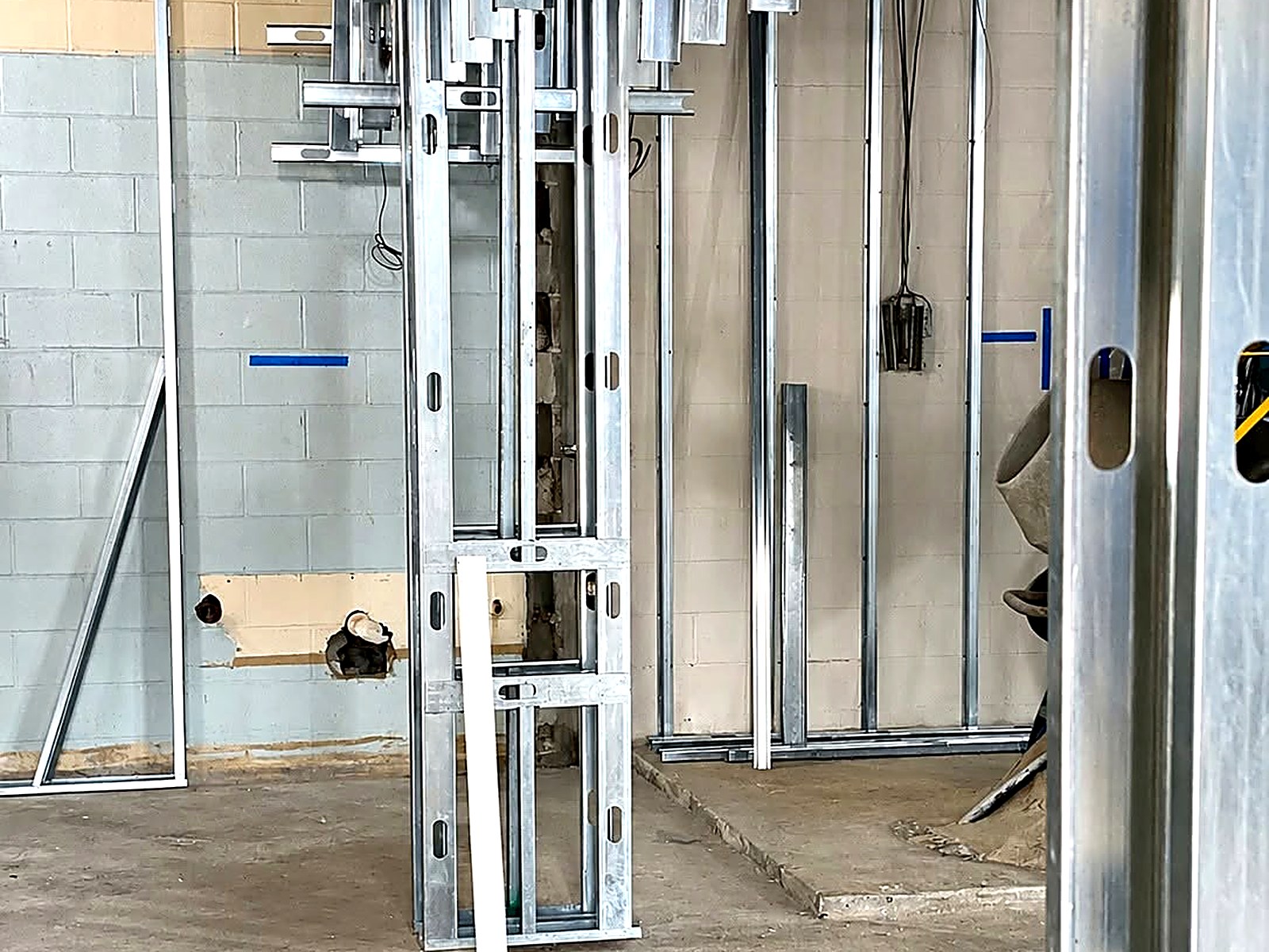 Metal stud shaft framing and strut supports set plumb against a block wall