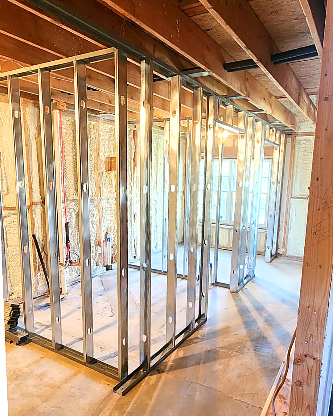 Metal stud partition framing installed against spray-foam insulated walls