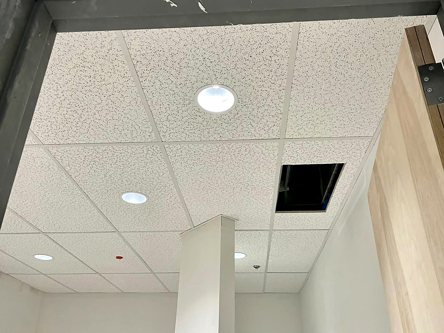 Acoustic tile ceiling grid with recessed downlights in a commercial space