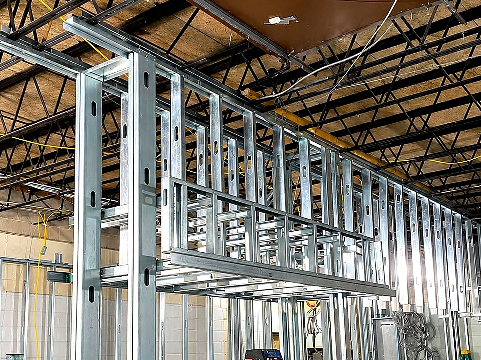 Heavy-gauge stud framing and header assembly under an open bar-joist roof