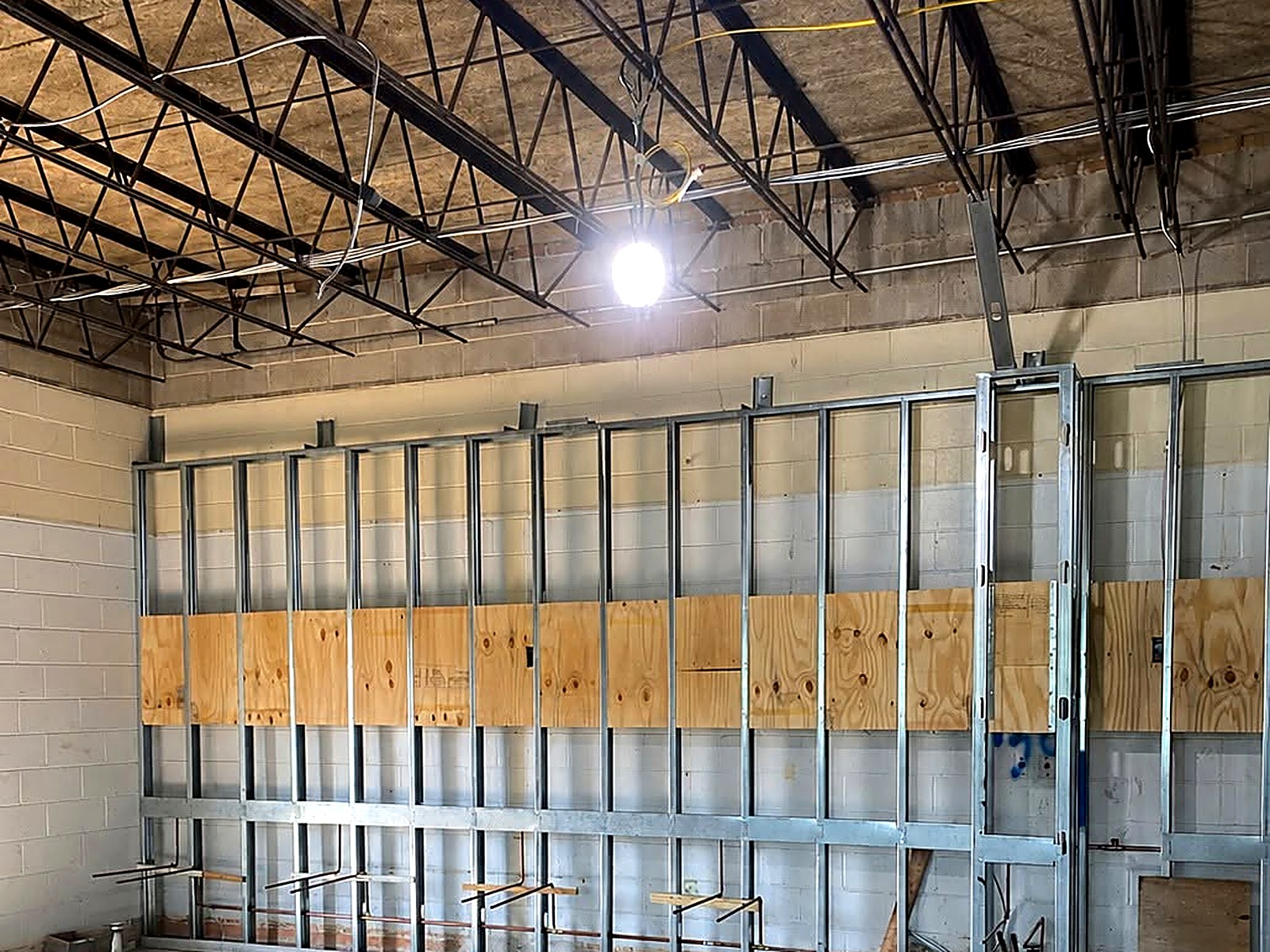 Full-height stud wall with plywood blocking and backing along a block wall