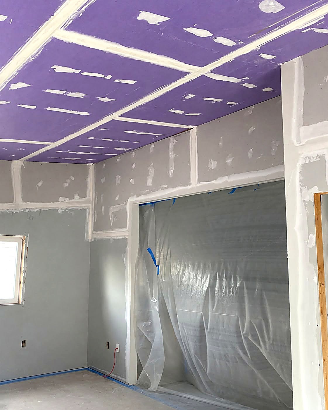 Fire-rated drywall ceiling and taped walls with dust protection in place