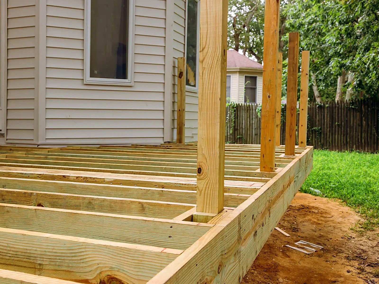 Pressure-treated deck frame with railing posts set for a new backyard deck