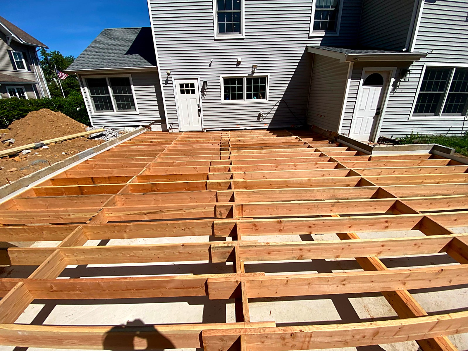 New deck floor framing with joists and blocking set over a concrete slab at a residence