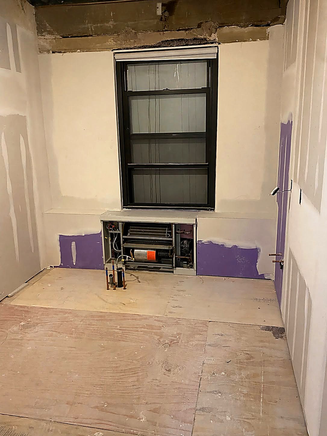 Taped drywall walls with moisture-resistant board around a window opening