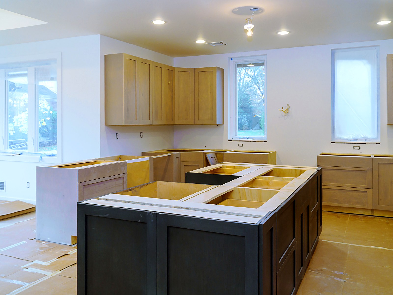 Kitchen renovation with upper and base cabinets installed and island framed