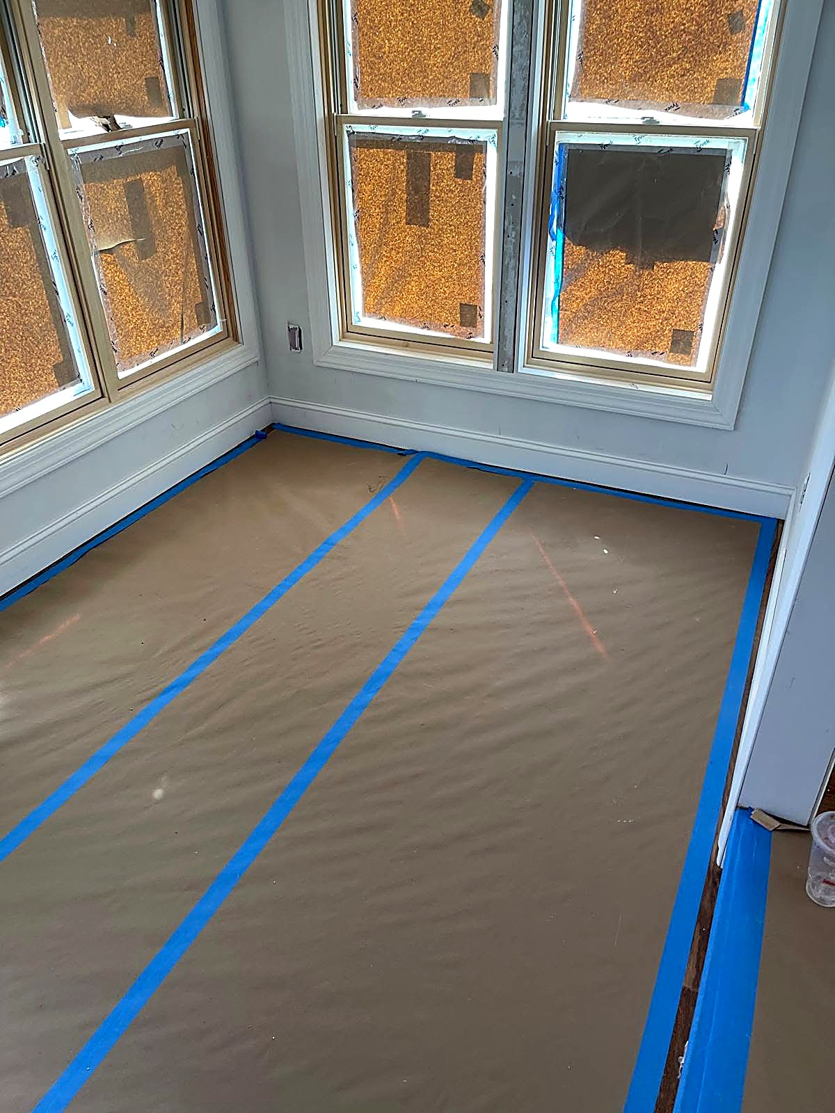Installed window trim and baseboard with floor protection in place