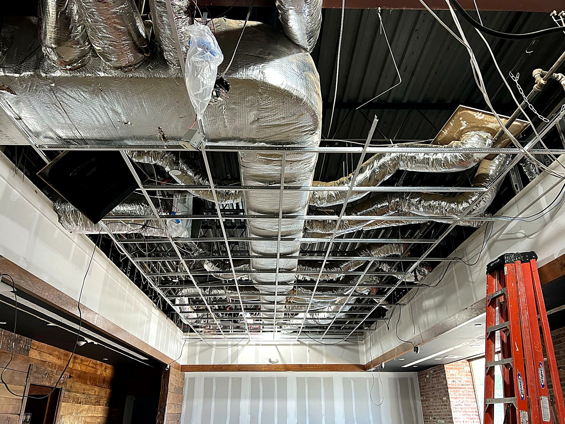 Ceiling grid installation coordinated around ductwork in a commercial fit-out