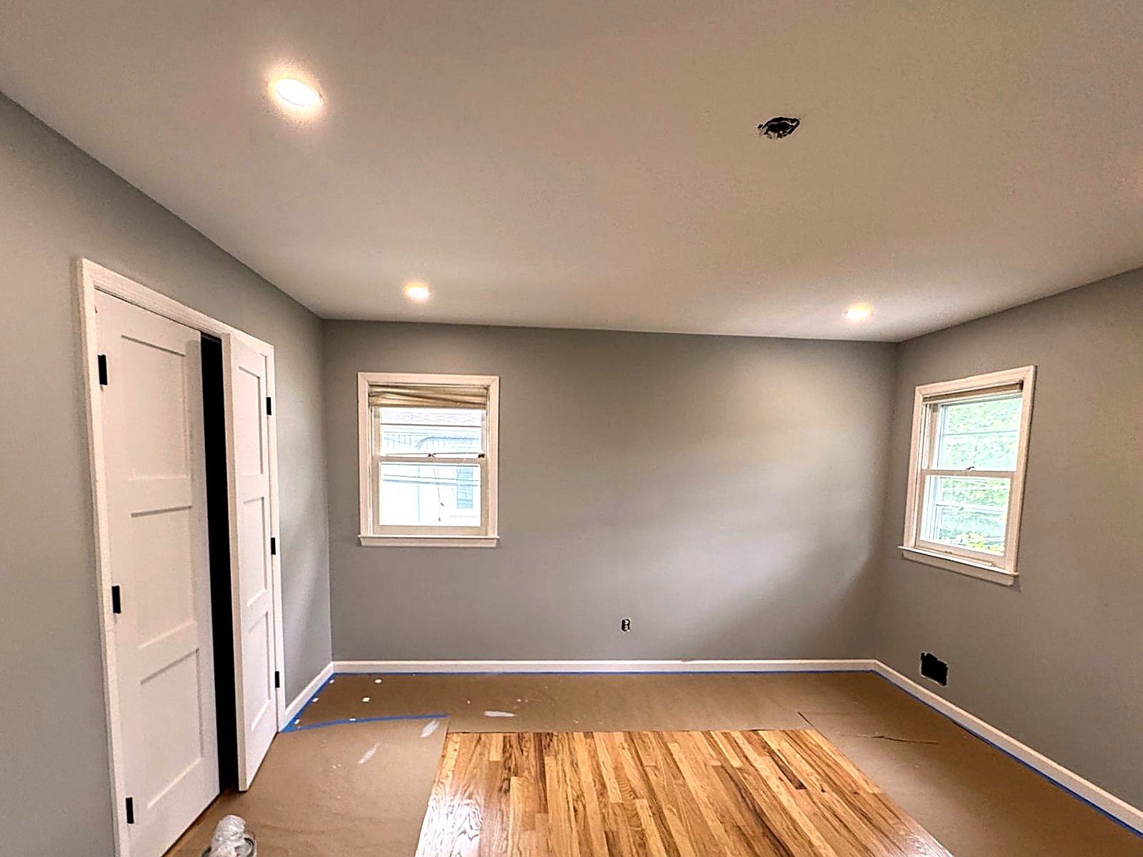 Grey bedroom repaint with white trim and masked floor protection