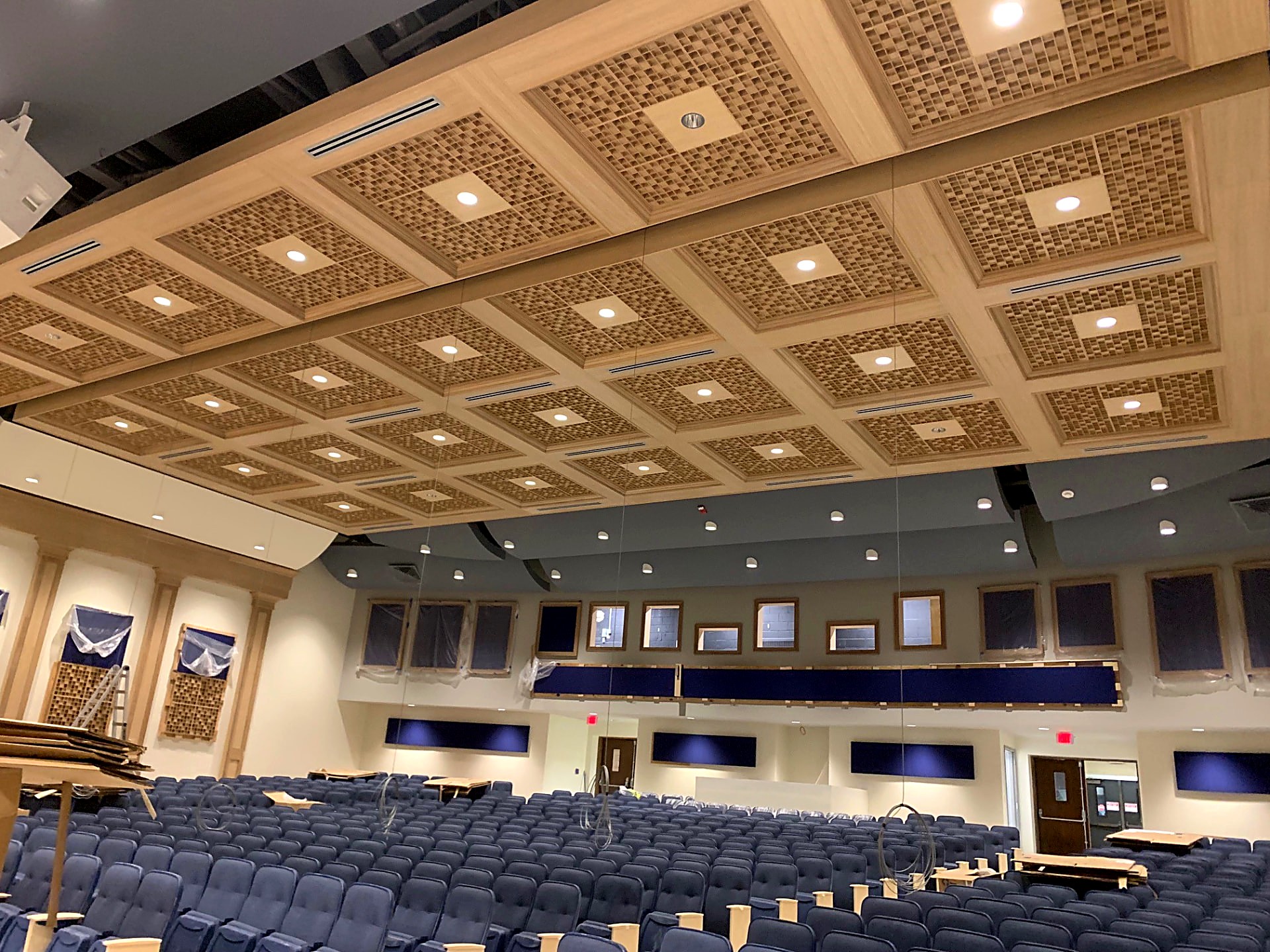 Custom wood coffered ceiling system with acoustic infill panels and recessed lighting in an auditorium