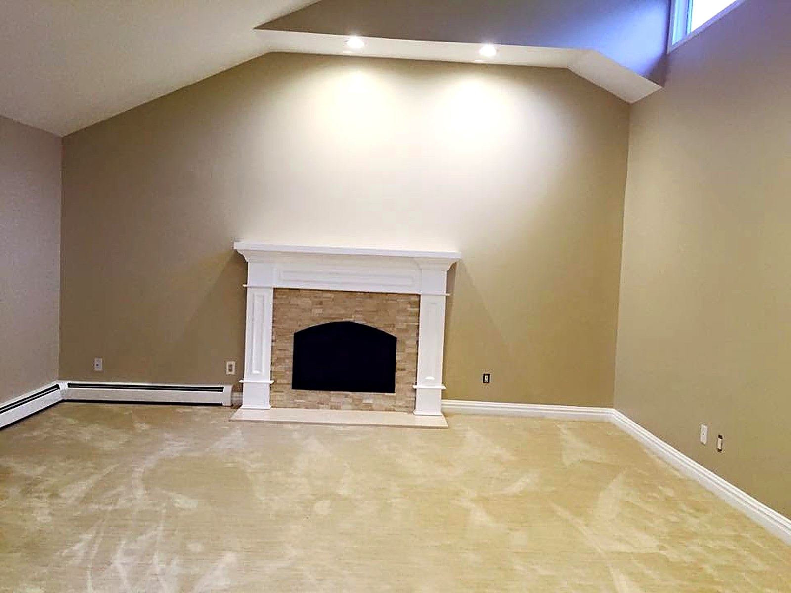 Freshly painted vaulted living space with white trim and mantel