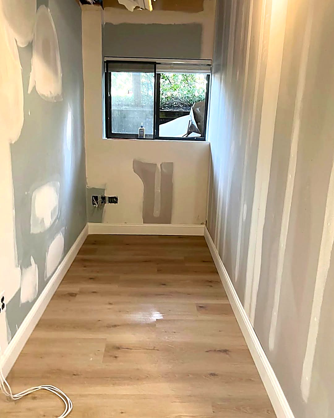 Drywall patching and skim coat repairs in a narrow interior room
