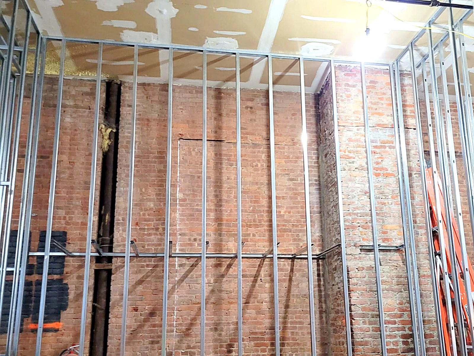 Stud framing furred out over an existing brick wall in a renovation