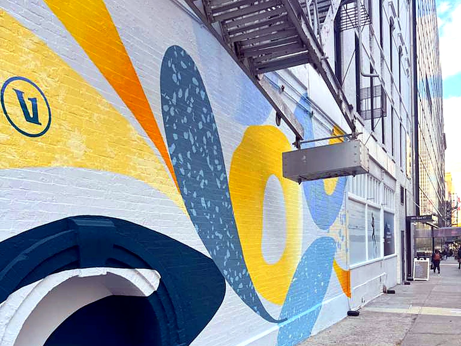 Large-scale painted mural on a repainted white masonry building facade