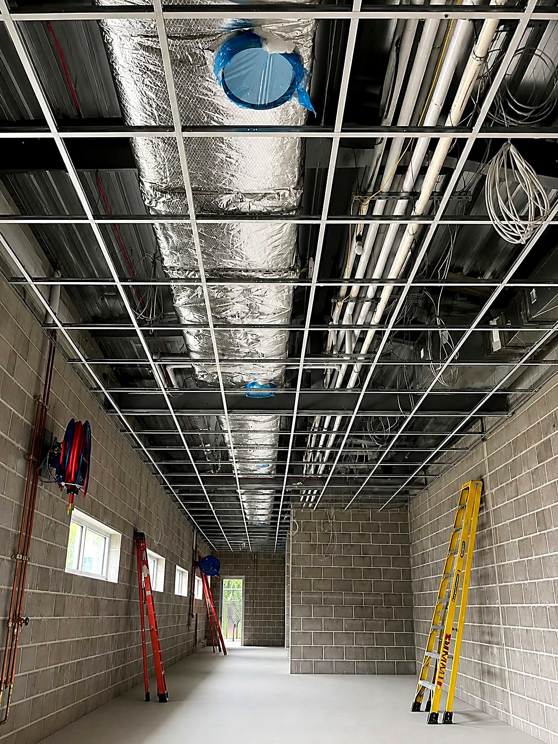 New suspended ceiling grid framed the full length of a masonry corridor