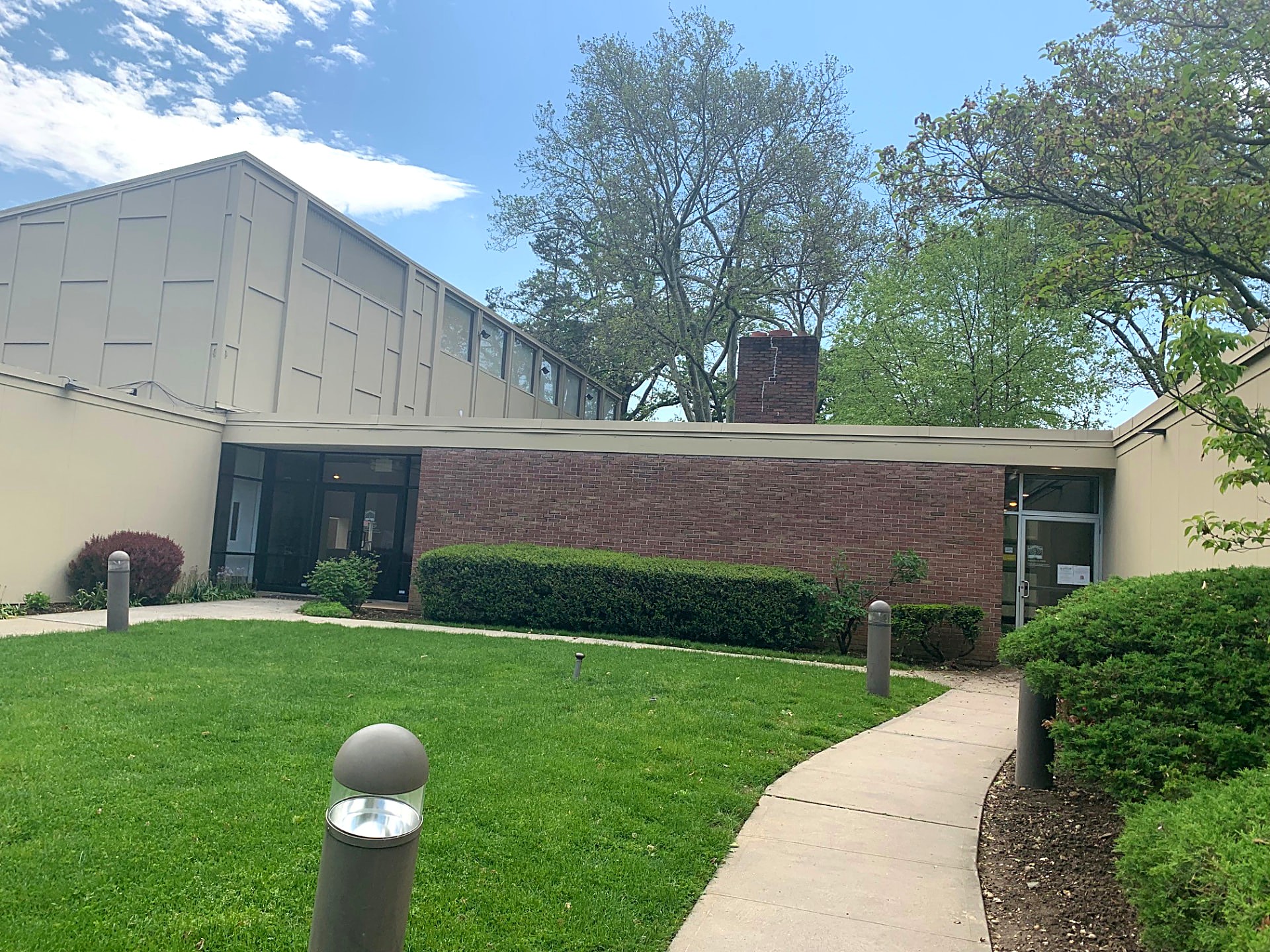 Institutional brick and panel building exterior with landscaped entry walk
